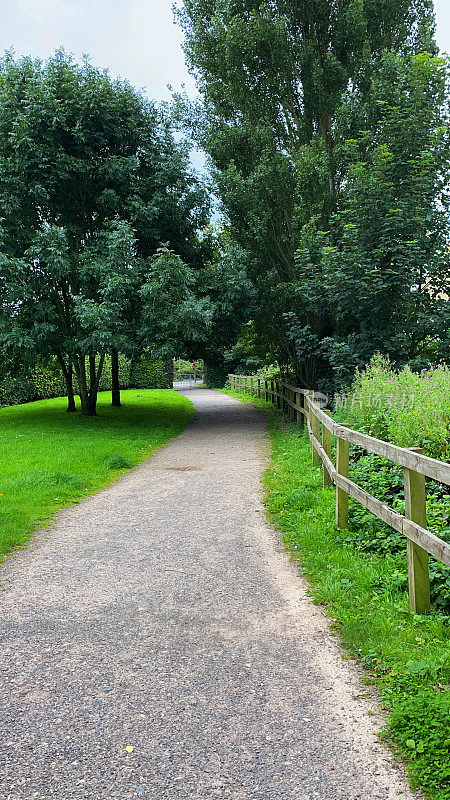 碎石、绿树成荫的小路穿过公园，还有木制的围栏