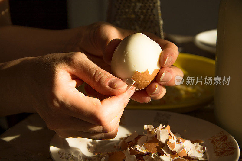 手剥煮鸡蛋。删除蛋壳。在厨房的餐桌上剥鸡蛋，做菜的配料，烹饪。