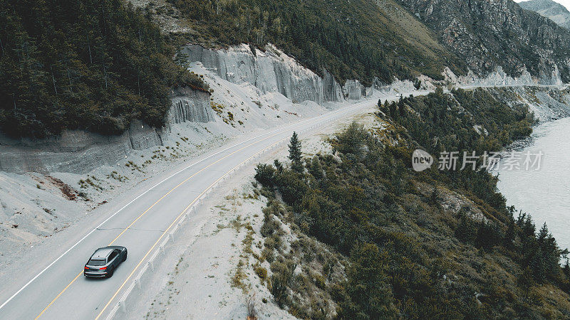 深灰色的汽车在山间的狭窄道路上行驶。无人机视频