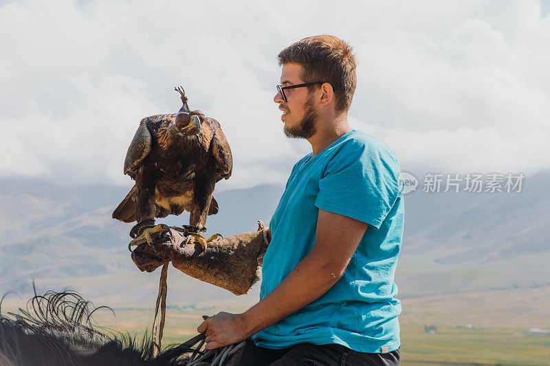 男人旅行者探索古老的传统与鹰猎人在中亚山区