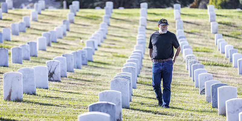 悲伤的越战美国海军老兵行走在军人公墓的墓碑之间