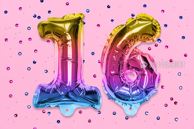彩虹箔气球号码，数字16在粉红色背景与亮片。有题字的生日贺卡