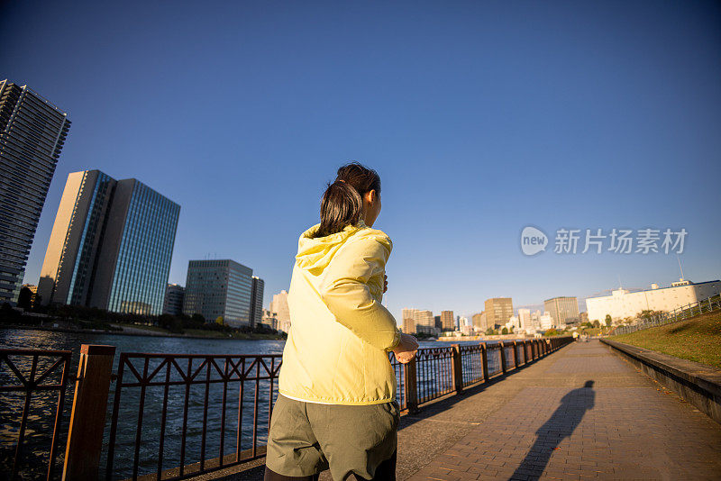 后视图的女人在河边跑步在城市