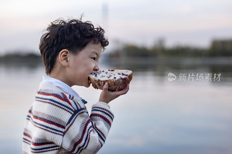 一个男孩正在户外吃面包