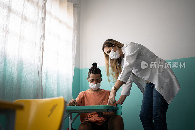 老师在教室里用口罩帮助学生上课