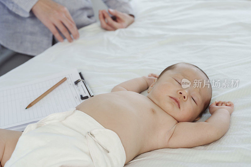 亚洲新生儿在床上不穿衬衫等待儿科医生检查，因为他在医院不适。