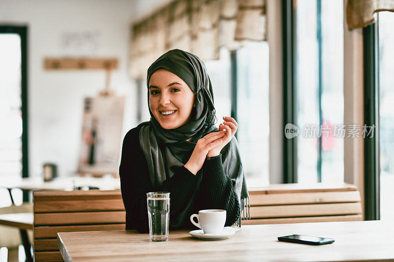 微笑的穆斯林女性享受美丽的一天与一杯咖啡