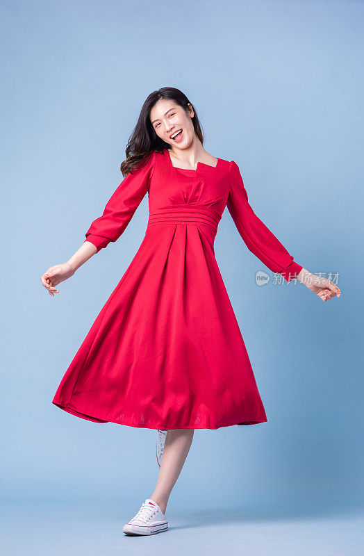 穿着蓝色背景的红色连衣裙的年轻亚洲妇女的全长图像