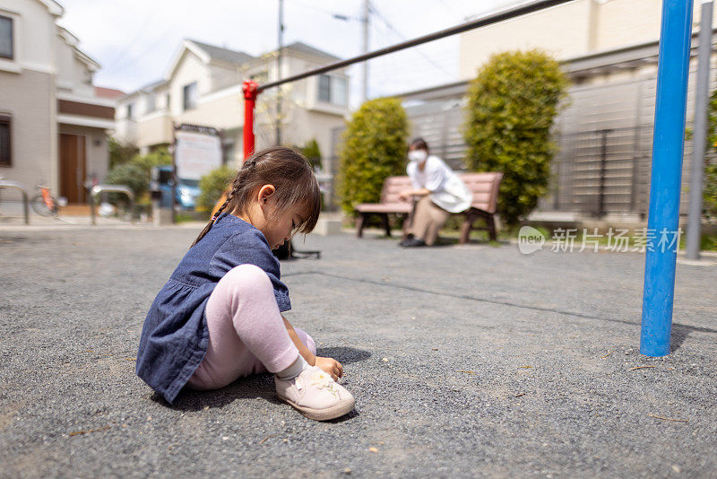 小女孩在公园里玩，妈妈坐在那里