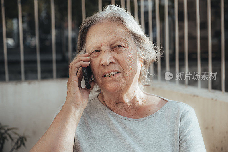 一位老妇人在阳台上打电话