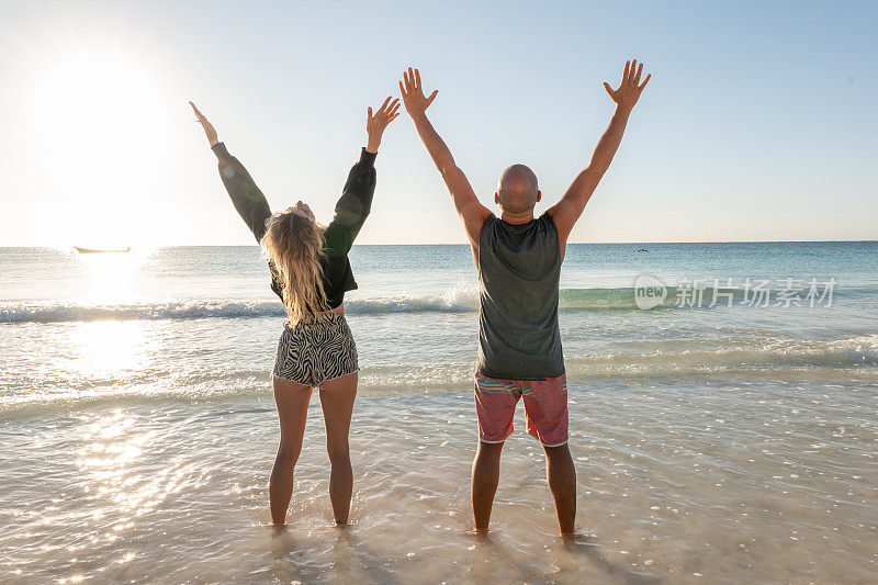 日出时分，夫妻俩在沙滩上享受大自然，双手合十，追求幸福