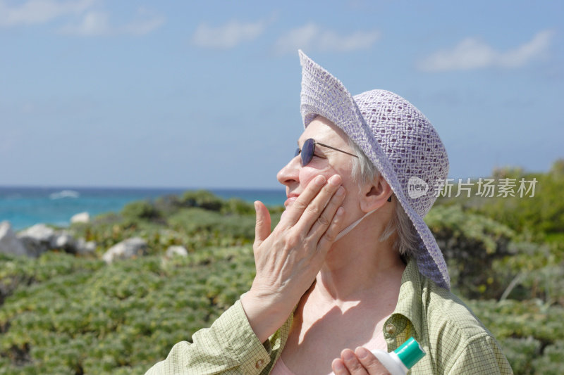 防晒-女人在太阳帽和太阳眼镜涂抹防晒霜