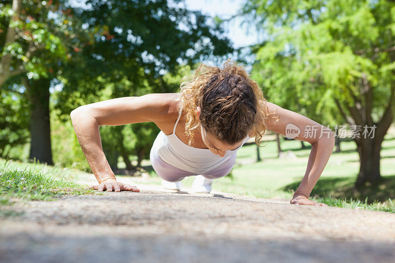 一个健康的女人在人行道上做俯卧撑