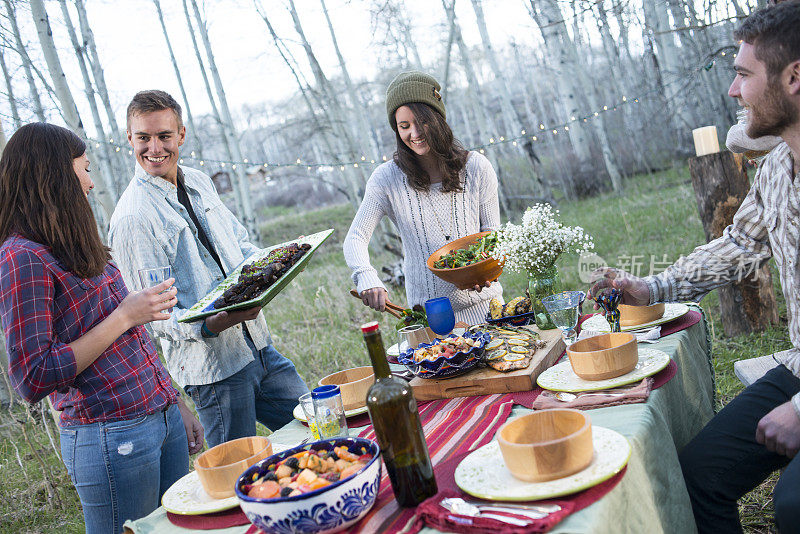 年轻的成年人在户外晚餐聚会在科罗拉多州的森林