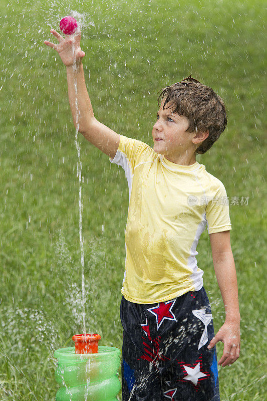 小男孩在院子里玩喷泉玩具球