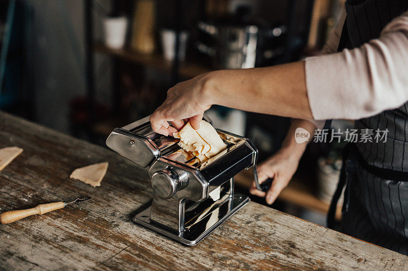 在意大利面制作机器上拉伸面团的女人