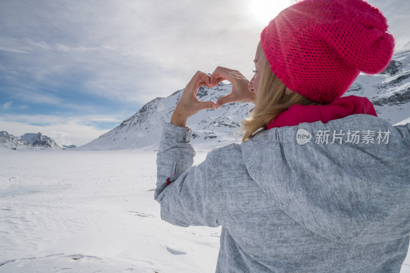 年轻女子在滑雪坡上做心形