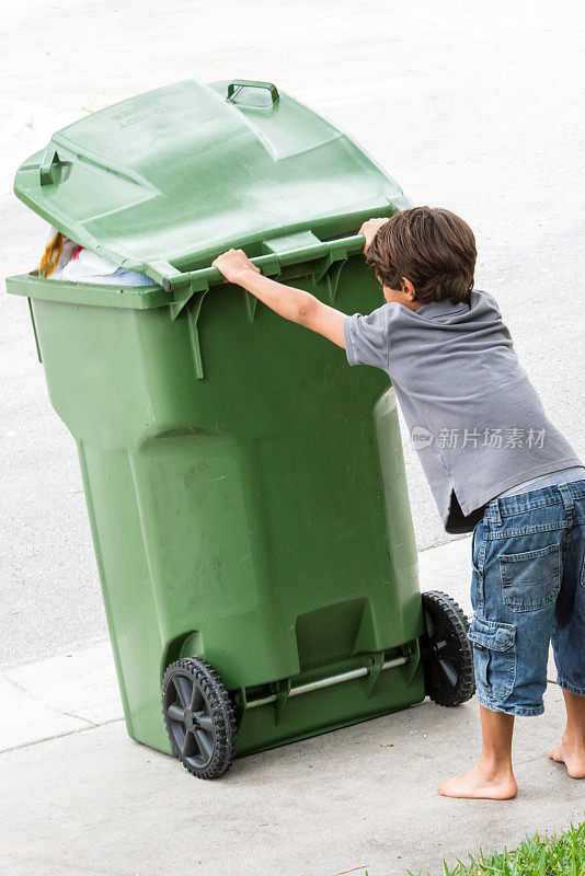一个孩子在移动一个带轮子的垃圾桶