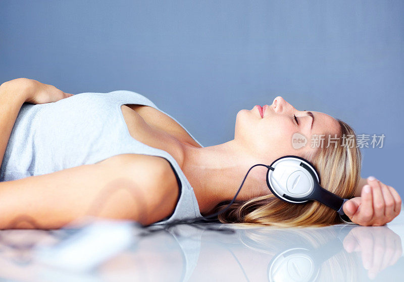 年轻的女士躺在地板上听音乐