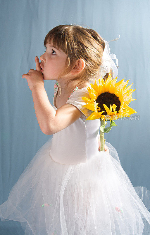 嘘!可爱的小女孩在白色芭蕾舞裙与向日葵