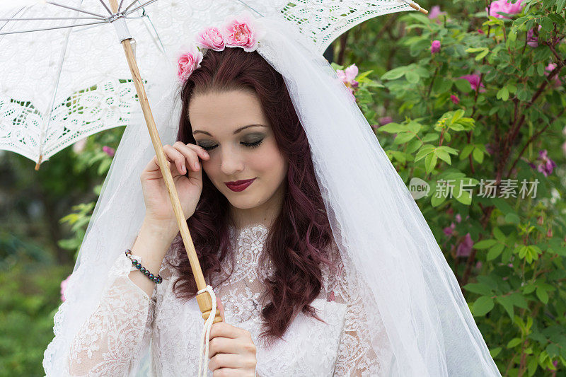 水平花园新娘肖像用花边遮阳伞，擦干眼泪。