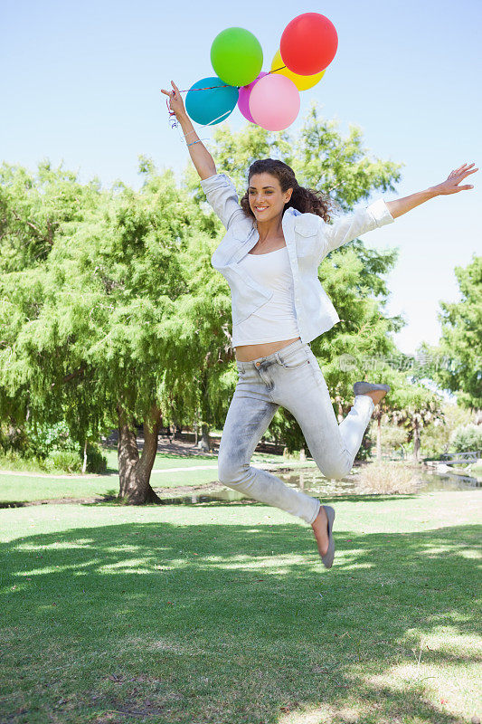 在公园里抱着一堆气球的蹦蹦跳跳的漂亮女人