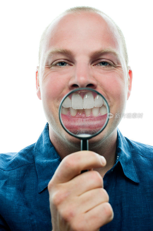 一个拿着放大镜遮住牙齿和嘴巴的男人