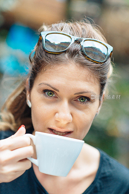 美丽的白人女人喝着咖啡，在夏天的下午微笑着