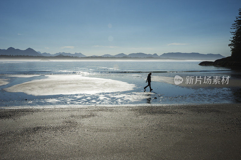 退潮时，女孩在海滩上行走的剪影