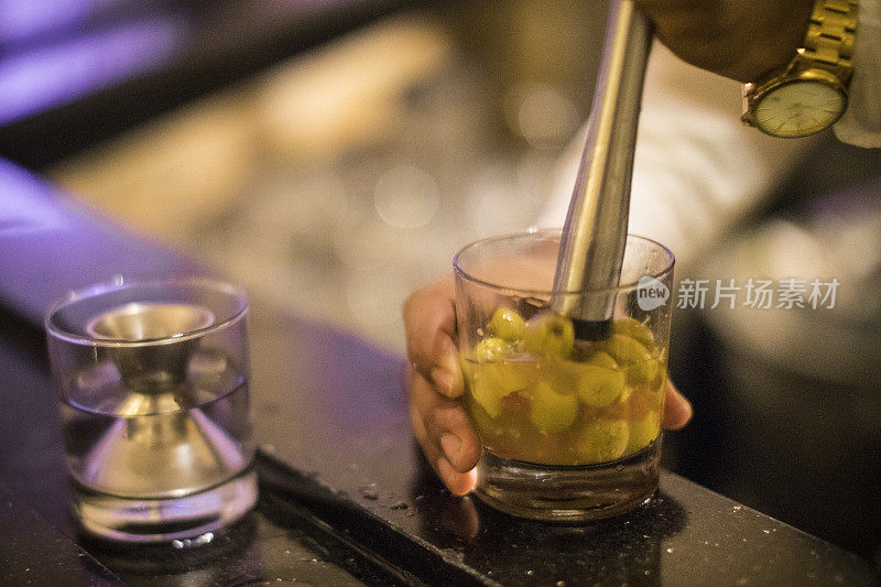 一个不知名的巴拿马调酒师正在压榨橄榄，准备一杯脏兮兮的马提尼。