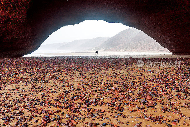 摄影师在摩洛哥海岸的拱形岩石下