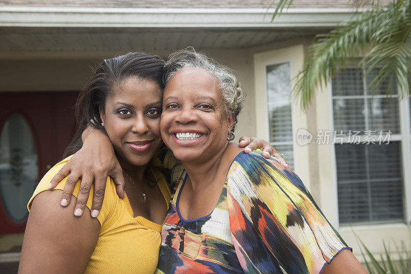 非裔美国人母亲和女儿在家前微笑