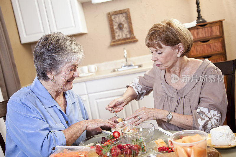 两位年长的女士在厨房的餐桌上准备午餐