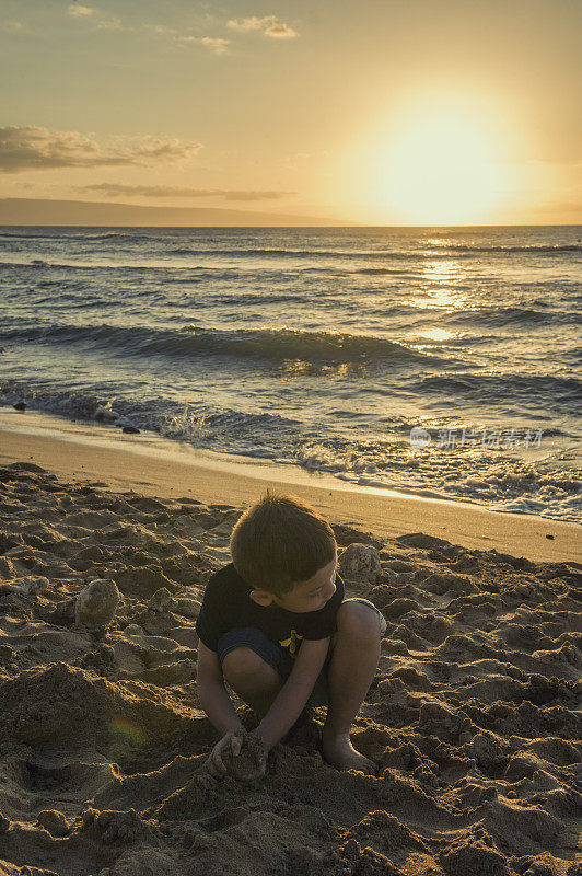 男孩在海滩上玩日落