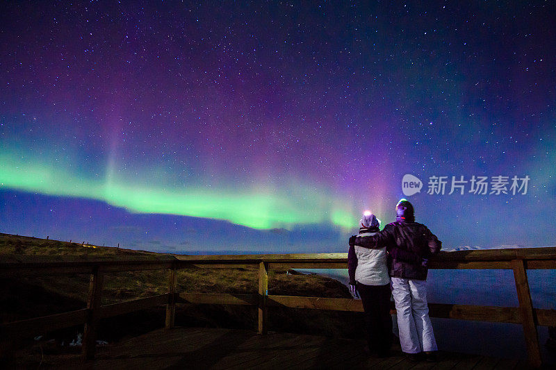 在冰岛，一对凝视北极光的情侣拥抱在一起