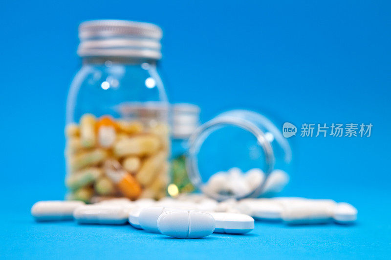 白色药丸和药片，药瓶在蓝色背景
