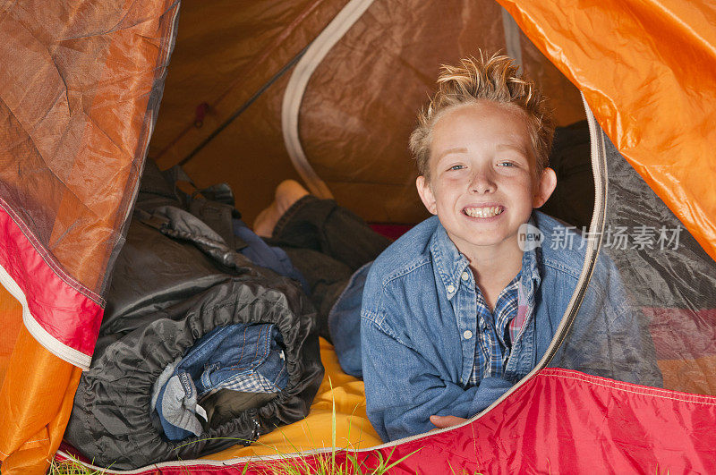 一个微笑的小男孩在帐篷里向外张望