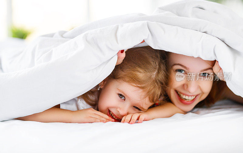 幸福的家庭妈妈和孩子女儿在床上笑