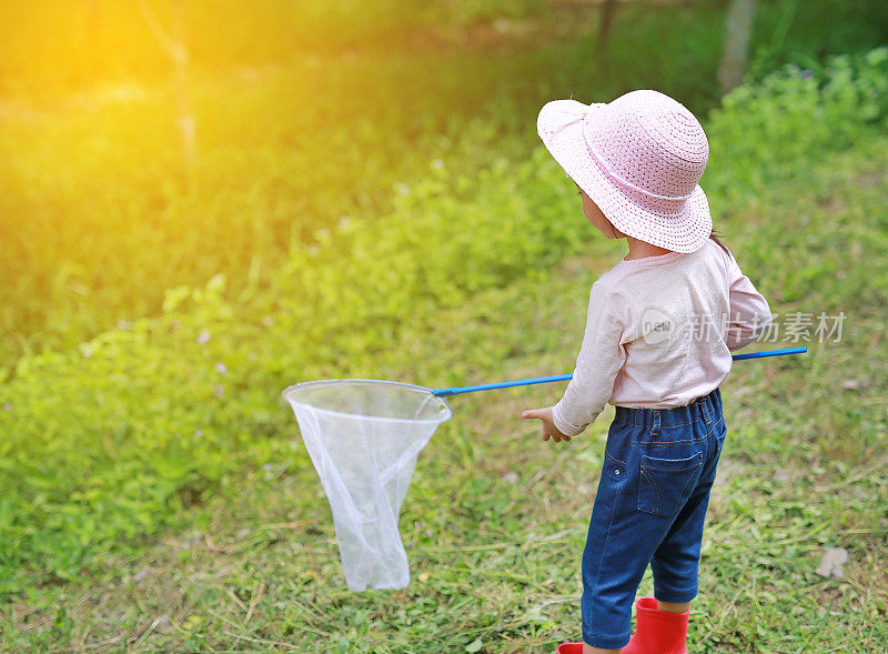 可爱的亚洲女孩戴着草帽和蚊帐在田野里玩夏天。