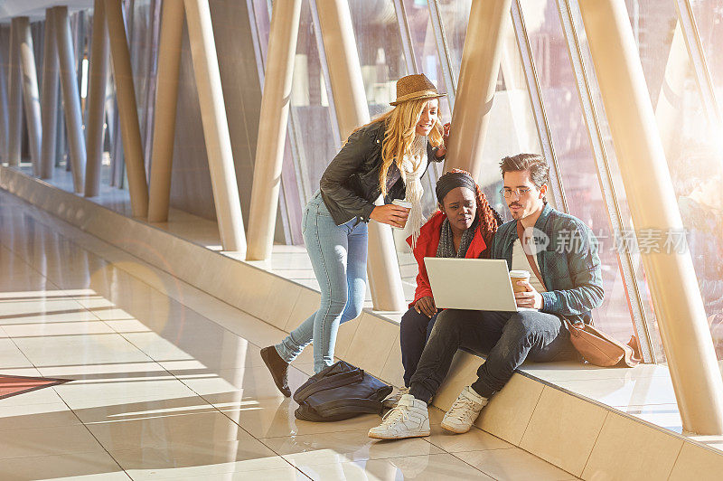 3名青年企业家或学生聚在笔记本电脑周围进行讨论