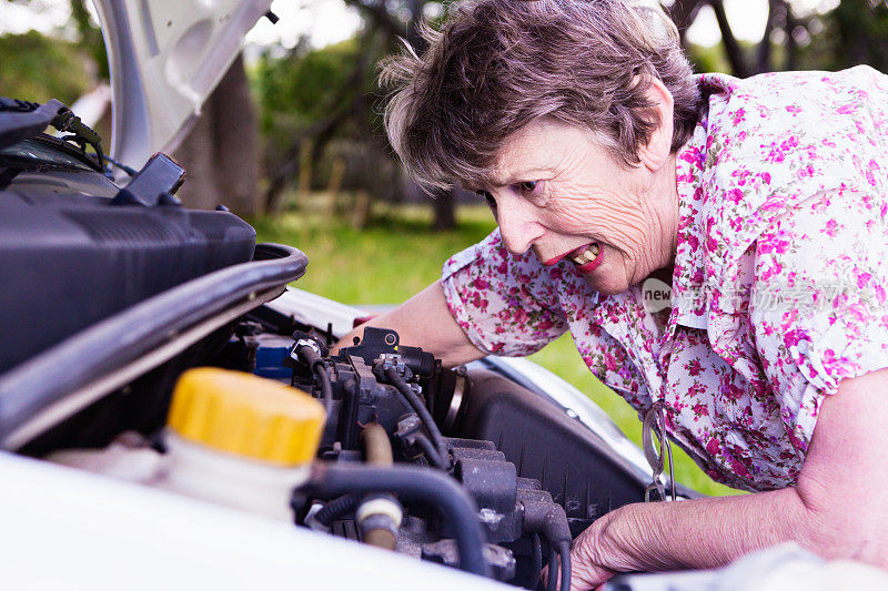 老妇人望着那辆坏了的汽车的发动机无可奈何