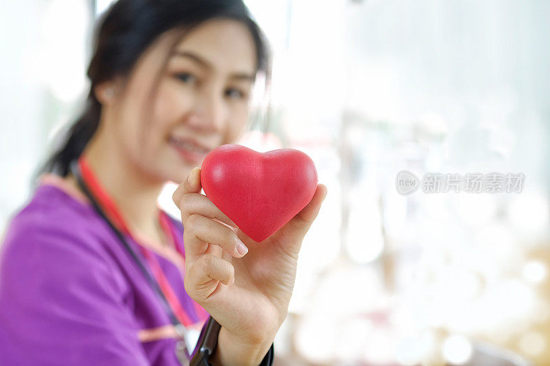 年轻的亚洲女孩，医学学生拿着心脏模型。女医生，用听诊器拿着心脏。
