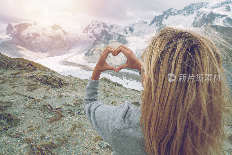 年轻女子在瑞士的冰川上造心