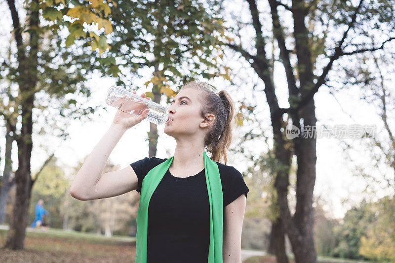 年轻的运动女孩在锻炼后喝水