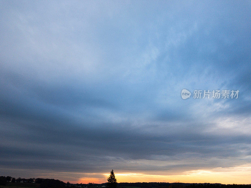 令人印象深刻的多云的蓝色天空和黄色温暖的日落光在地平线上