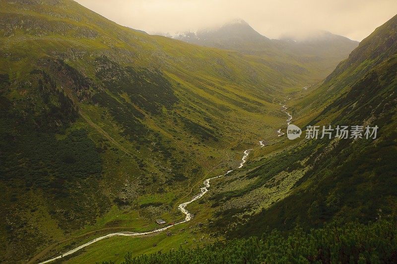 童话般的风景:上面的小河流水进入迷雾般田园诗般的高山谷地和草地，戏剧性的瑞士雪山，田园诗般的乡村，格劳宾登，瑞士阿尔卑斯山