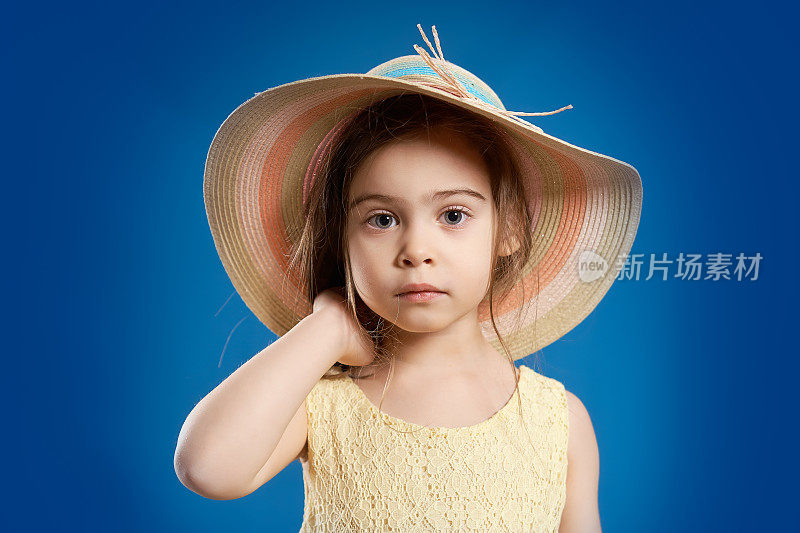 漂亮的小女孩，穿着黄色的裙子，戴着一顶夏天的帽子