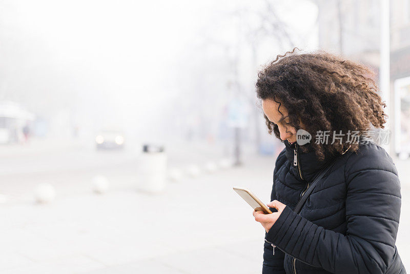 一位严肃的女士在雾中看着她的手机