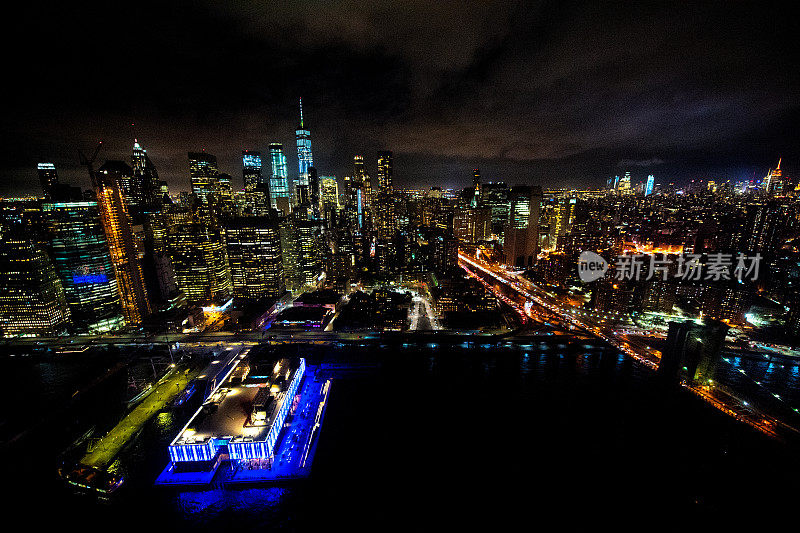 直升机拍摄的布鲁克林大桥旁东河上曼哈顿下城的夜景