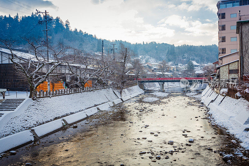 雪山村日出与红色木桥和小溪，日本